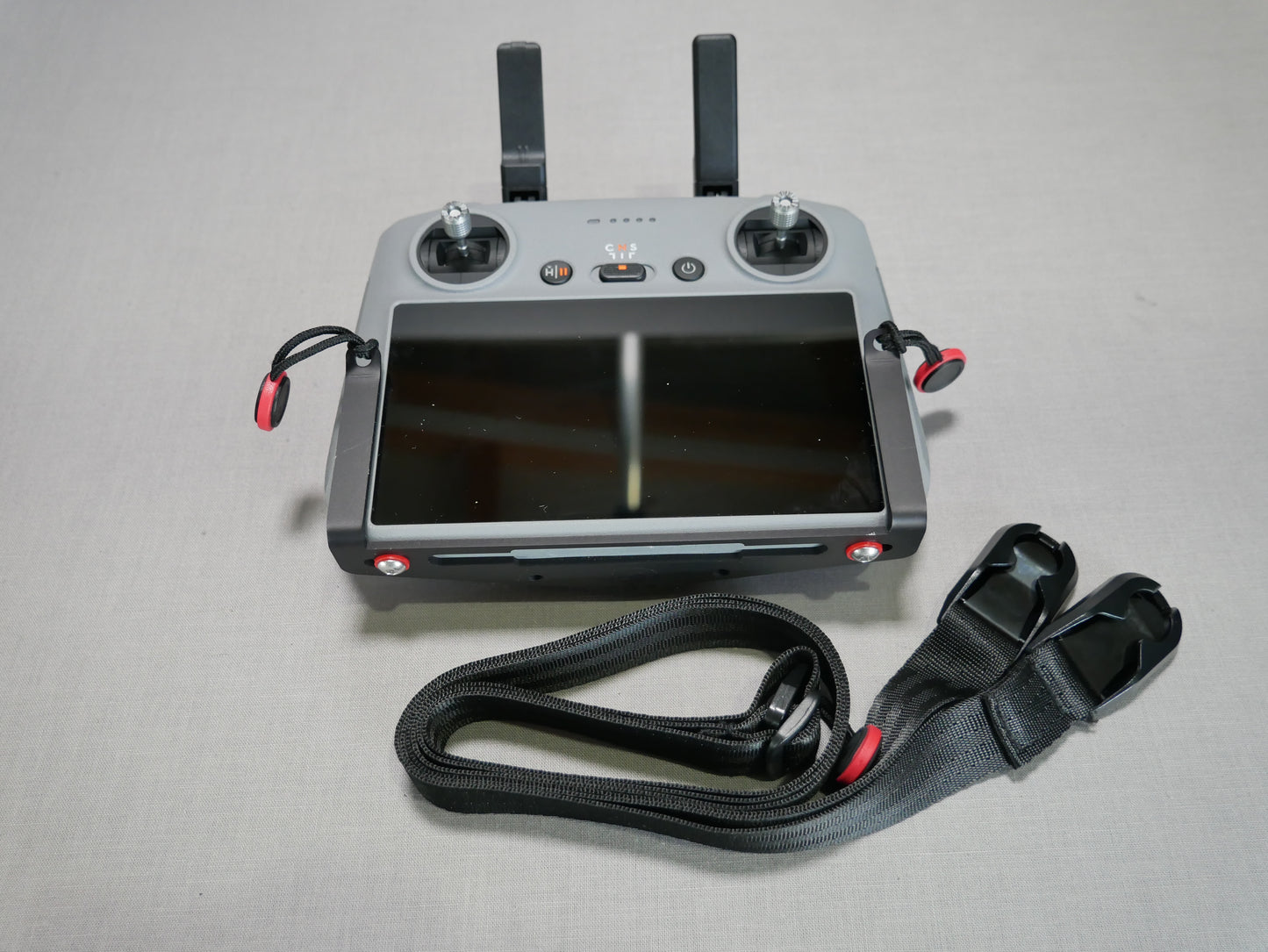 Halter mit daneben liegendem Halsgurt in schwarz am DJI RC/RC 2 Controller angebracht