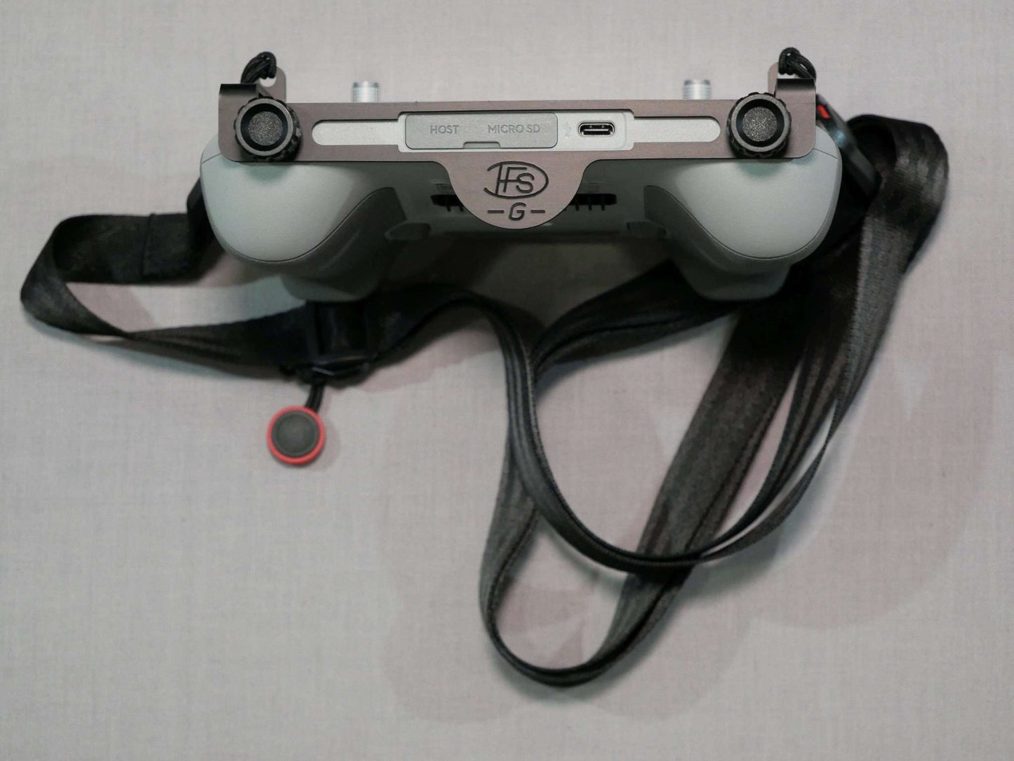 Halter mit Halsgurt in schwarz befestigt an DJI RC-N2 Controller. Vorderansicht